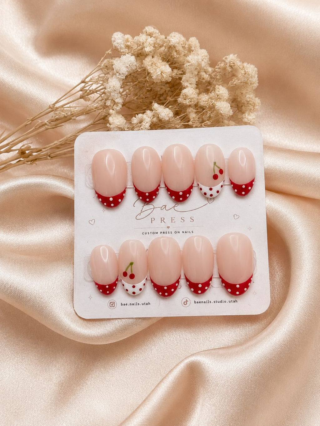 Cherry Kiss press-on nails with nude base and cherry red French tips